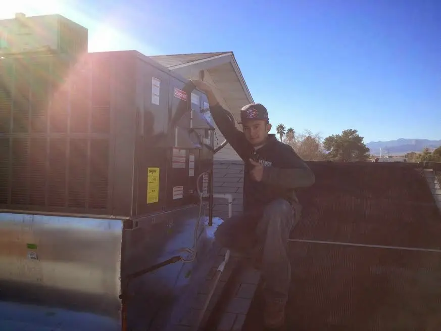 HVAC technician performing Air Duct Cleaning on a rooftop unit in Harrison